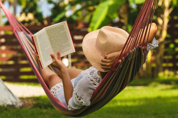 Beautiful Woman Relaxing In Hammock. Beautiful Woman Reading Boo Beautiful woman relaxing in hammock. Beautiful woman reading book in hammock. Happy beautiful woman in white dress relaxing in hammock. Beautiful woman in vacation. Vacation. Hammock. Tropical garden.